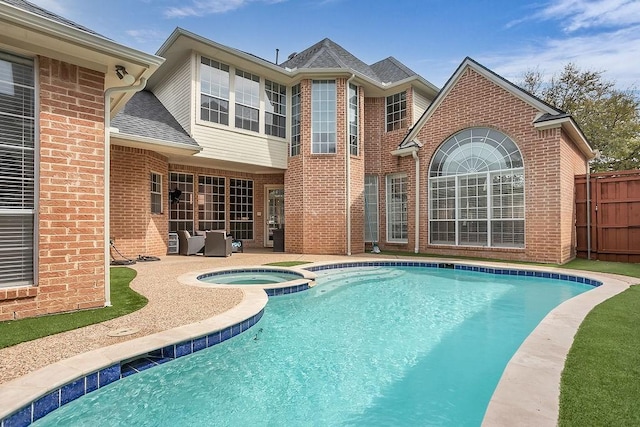 view of swimming pool with a patio area, a pool with connected hot tub, and fence