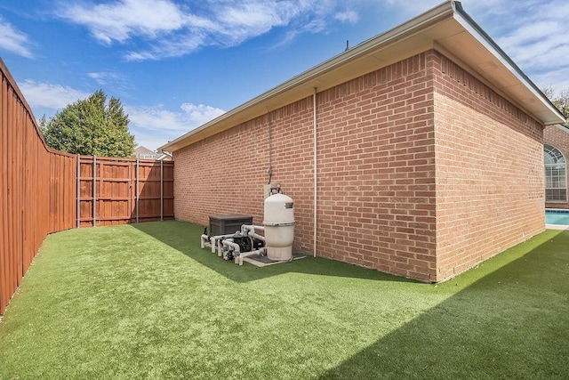 view of side of property featuring a yard, a fenced backyard, and brick siding