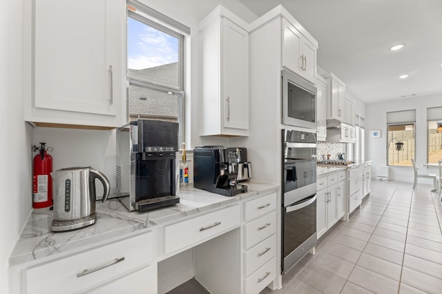 kitchen featuring stainless steel appliances, tasteful backsplash, white cabinets, and light tile patterned flooring