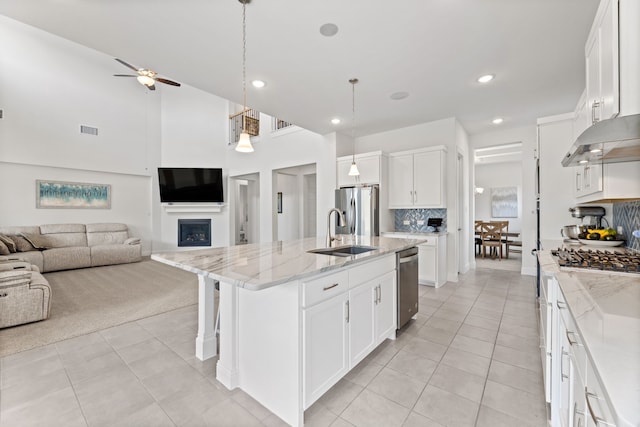 kitchen with visible vents, appliances with stainless steel finishes, open floor plan, a fireplace, and a sink