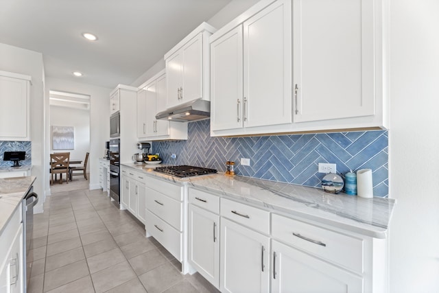 kitchen featuring under cabinet range hood, light tile patterned floors, appliances with stainless steel finishes, and white cabinets