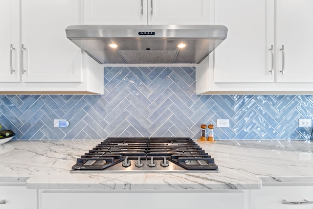 kitchen featuring stainless steel gas stovetop, backsplash, white cabinets, and range hood