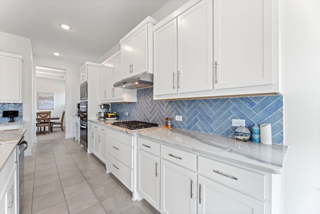 kitchen featuring backsplash, white cabinetry, light tile patterned floors, and under cabinet range hood