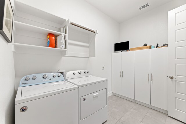 clothes washing area featuring cabinet space, light tile patterned floors, visible vents, and washer and clothes dryer