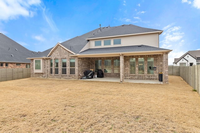 back of house with a fenced backyard, a patio, and brick siding