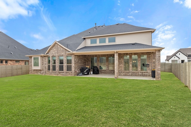 rear view of property with a patio, a fenced backyard, a yard, and brick siding
