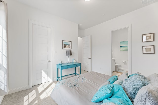 bedroom with ensuite bathroom, carpet flooring, visible vents, and baseboards