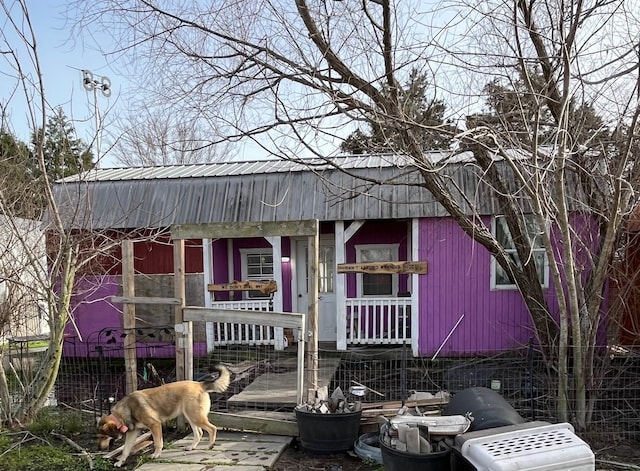 view of front of property featuring metal roof and fence