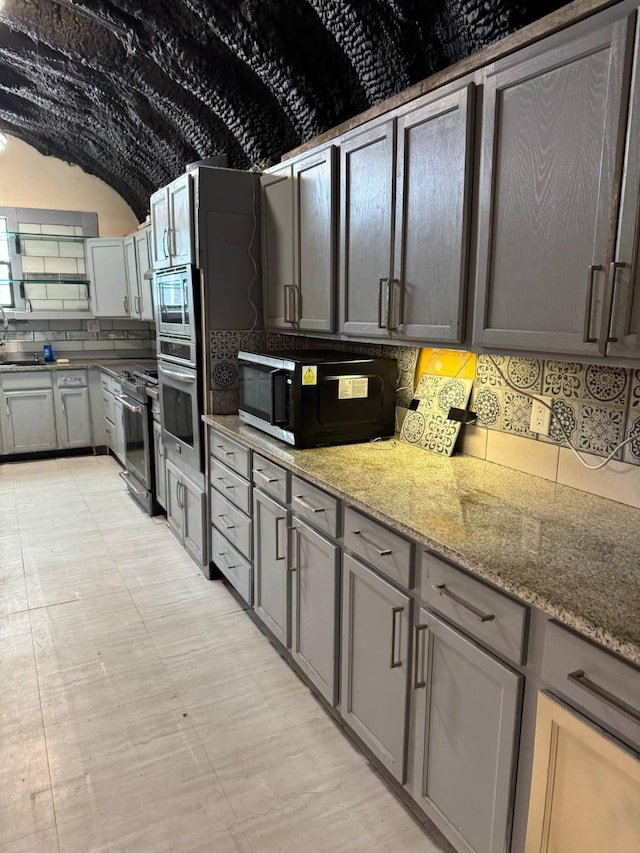 601 Pritchett Ln, Kemp, TX 75143 - kitchen with stainless steel appliances, tasteful backsplash, light stone counters, and vaulted ceiling
