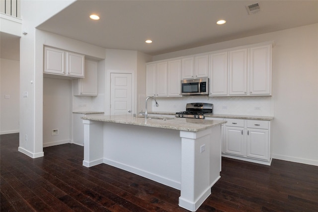 kitchen with a sink, visible vents, white cabinetry, appliances with stainless steel finishes, and a center island with sink