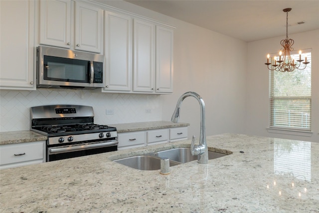 kitchen featuring backsplash, white cabinetry, stainless steel appliances, and a sink