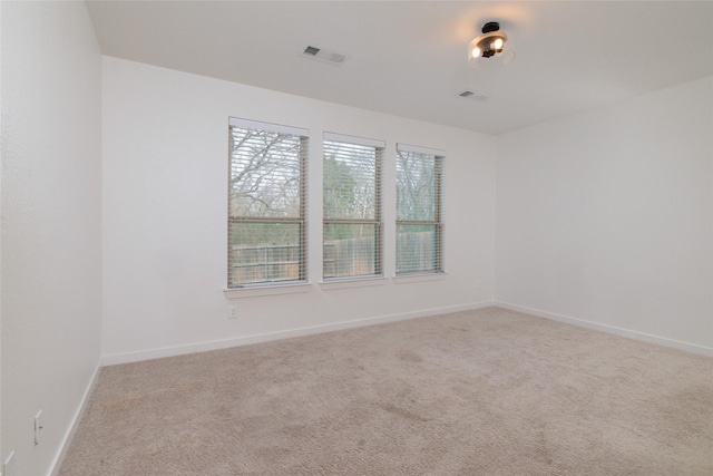 carpeted spare room featuring visible vents and baseboards