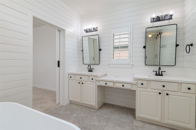 full bath featuring a freestanding bath, two vanities, and a sink