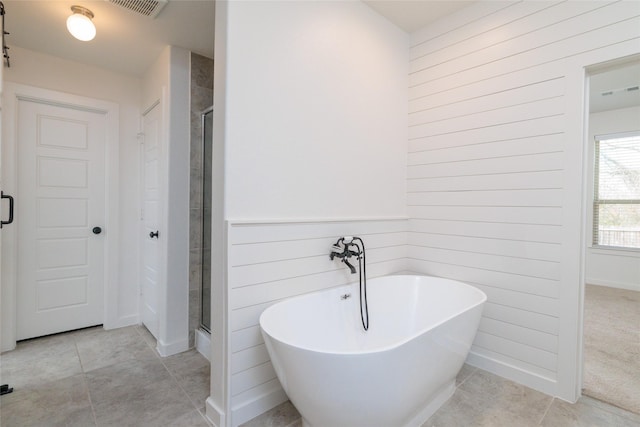 bathroom with tile patterned flooring, a freestanding tub, visible vents, and a shower stall