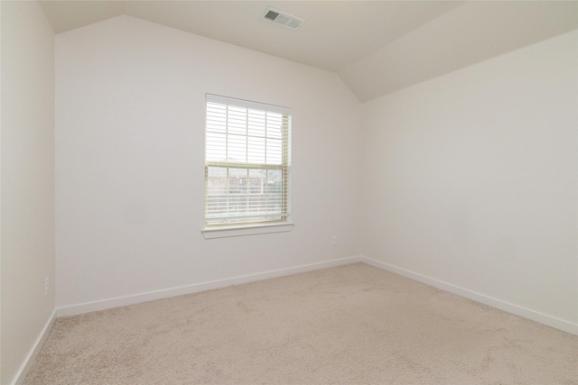 empty room featuring carpet, visible vents, vaulted ceiling, and baseboards