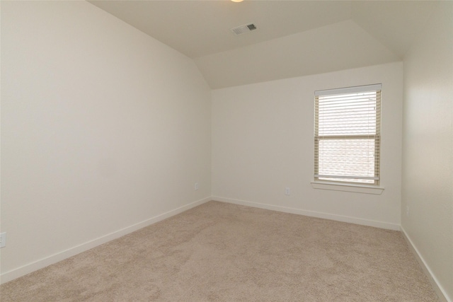 empty room with lofted ceiling, visible vents, light carpet, and baseboards