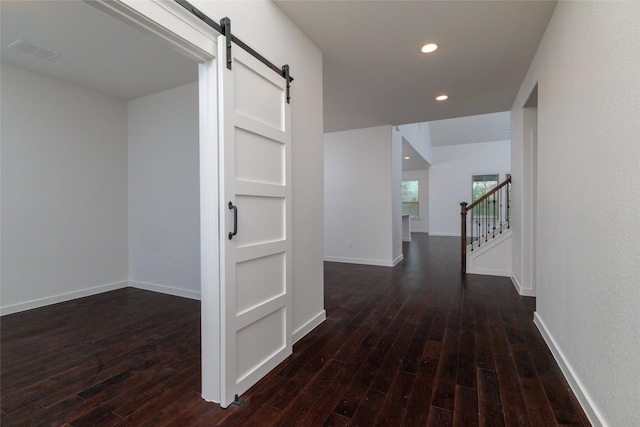 hall with a barn door, recessed lighting, visible vents, stairs, and dark wood finished floors