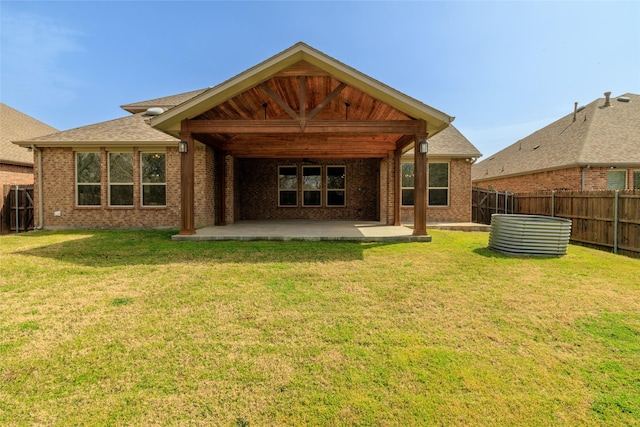 rear view of house with a patio area, brick siding, a fenced backyard, and a lawn