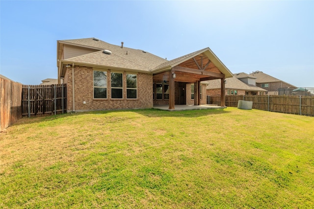 back of house featuring a patio area, a fenced backyard, a lawn, and brick siding