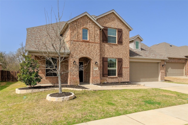 traditional-style home with a garage, driveway, a front yard, and brick siding