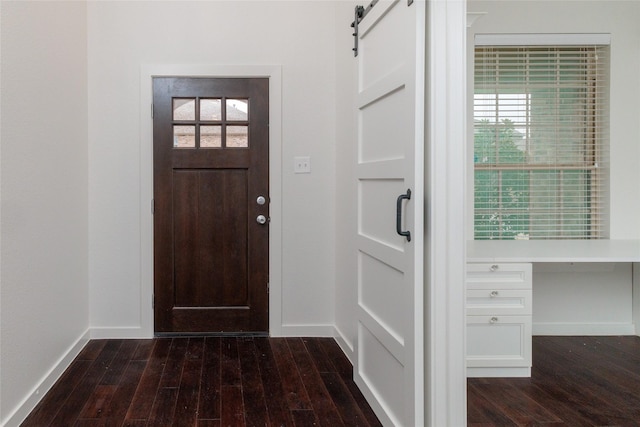 entrance foyer featuring a healthy amount of sunlight, a barn door, baseboards, and dark wood-style flooring