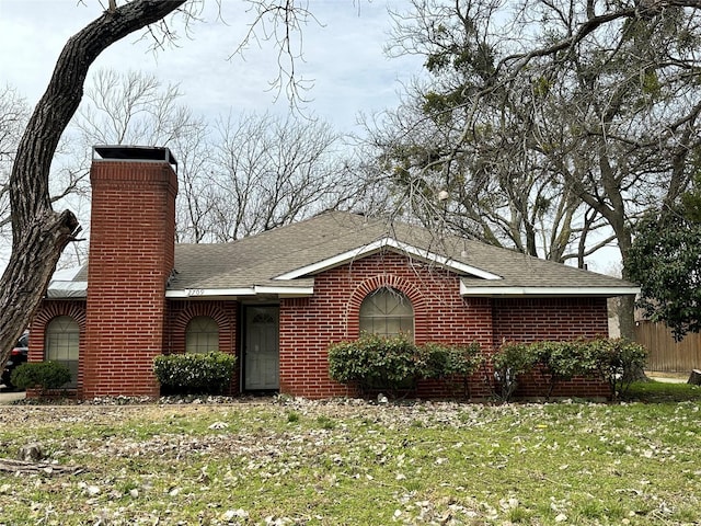 ranch-style home featuring a shingled roof, brick siding, and a front lawn