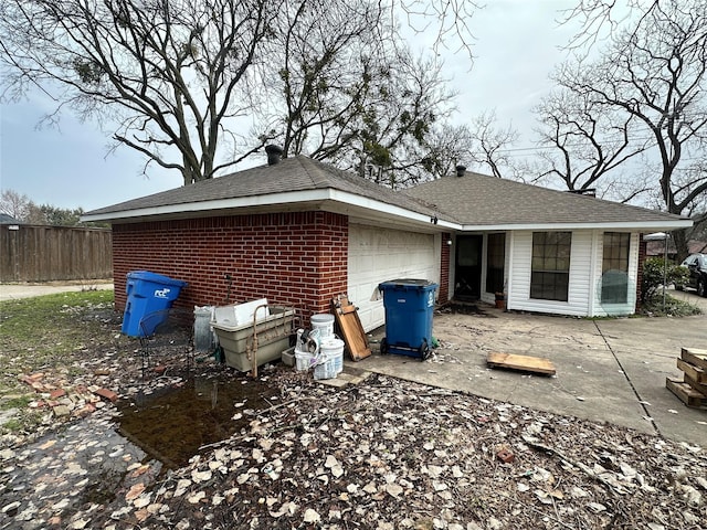 view of side of property featuring brick siding, an attached garage, and fence