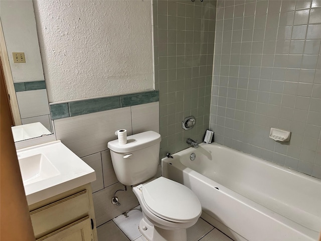 bathroom featuring a textured wall, toilet, vanity, shower / bathtub combination, and tile walls