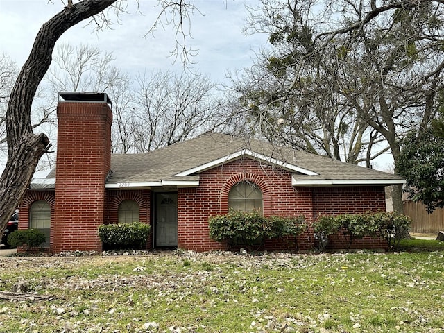 single story home featuring a front yard, brick siding, a chimney, and roof with shingles