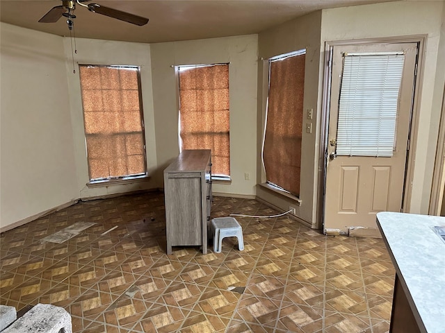 foyer entrance featuring a ceiling fan and baseboards