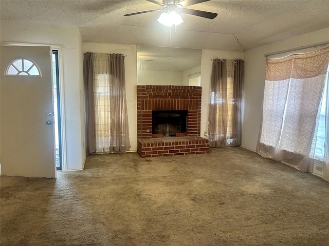 unfurnished living room featuring carpet, a brick fireplace, vaulted ceiling, ceiling fan, and a textured ceiling