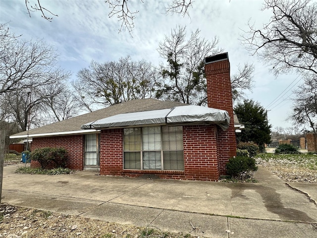 exterior space with brick siding and a chimney