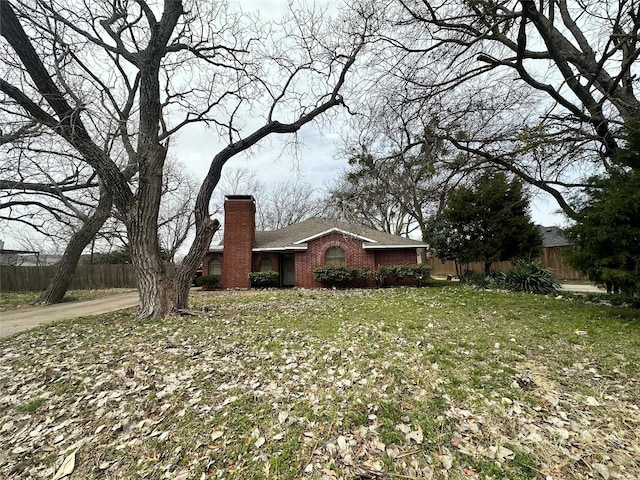 view of property exterior with brick siding, fence, a chimney, and a lawn