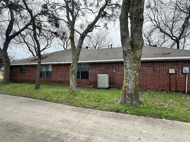 view of property exterior featuring central air condition unit, a lawn, and brick siding