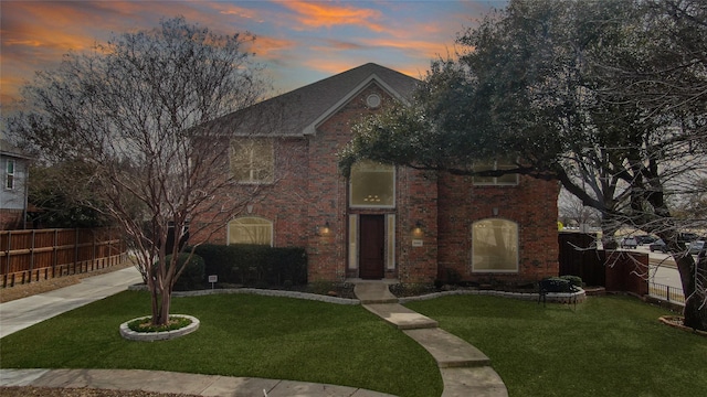 view of front of home featuring a yard, fence, and brick siding