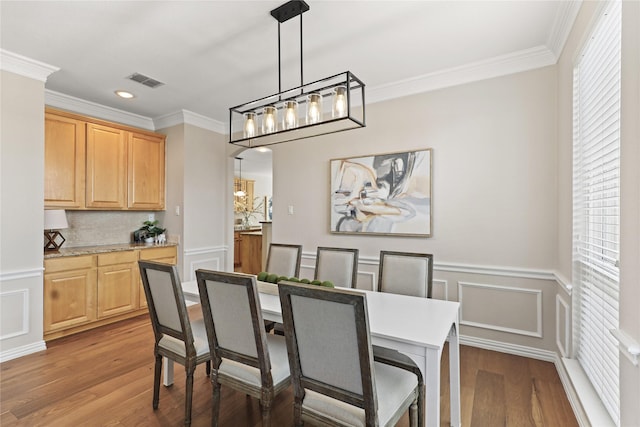 dining space with visible vents, crown molding, and light wood finished floors