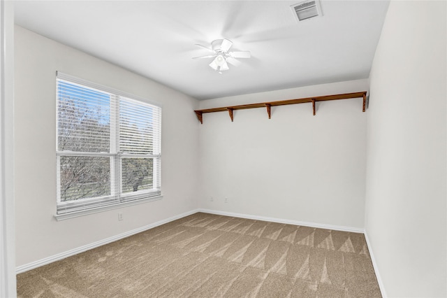 empty room featuring light carpet, visible vents, a ceiling fan, and baseboards