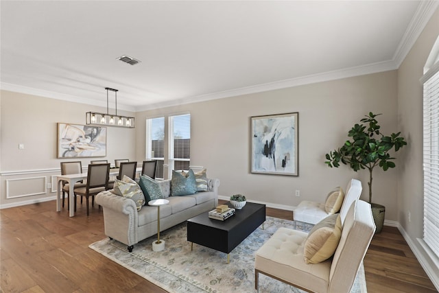 living room featuring a chandelier, visible vents, ornamental molding, and wood finished floors