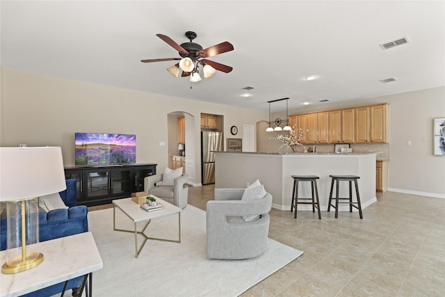 living room featuring visible vents, arched walkways, baseboards, and ceiling fan