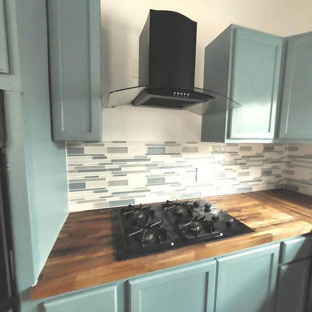 kitchen featuring wall chimney exhaust hood, butcher block countertops, black gas stovetop, and decorative backsplash