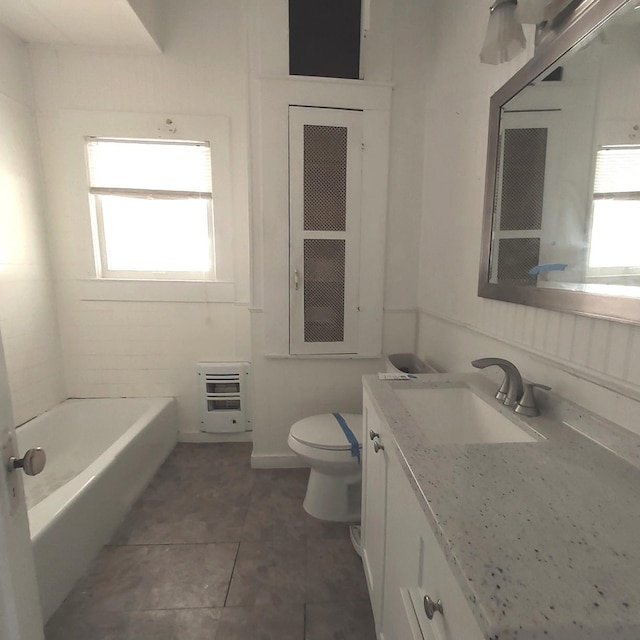 bathroom featuring a washtub, heating unit, toilet, vanity, and tile patterned flooring