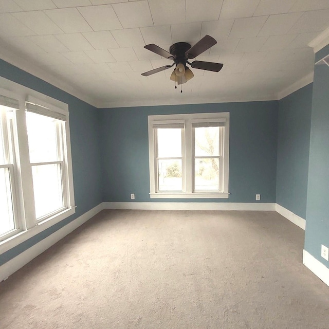 carpeted empty room featuring crown molding, ceiling fan, and baseboards