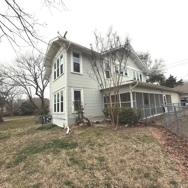 rear view of property with a lawn, fence, and a sunroom