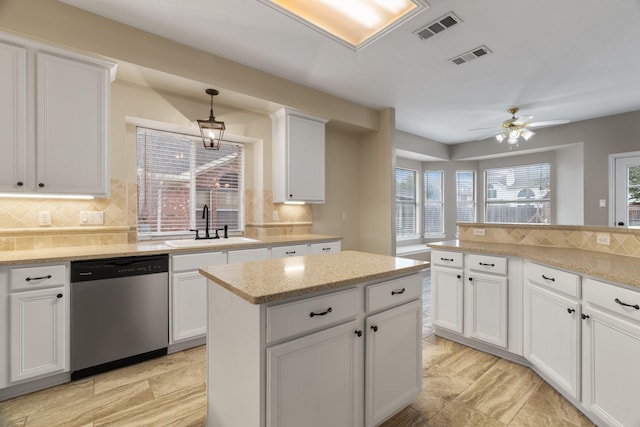 kitchen featuring stainless steel dishwasher, backsplash, a sink, and visible vents