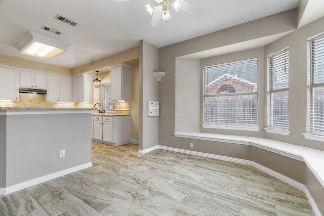 kitchen with light countertops, visible vents, backsplash, and white cabinetry