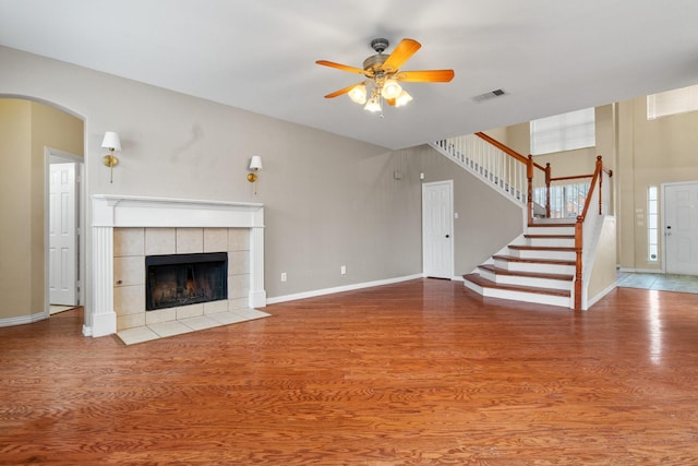 unfurnished living room featuring stairs, visible vents, wood finished floors, and a tiled fireplace