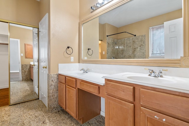 full bathroom with double vanity, a sink, and tiled shower