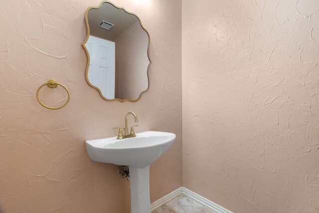 bathroom featuring a textured wall, visible vents, and baseboards