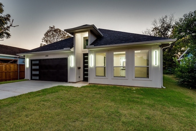 view of front of home featuring a garage, driveway, fence, and a front lawn