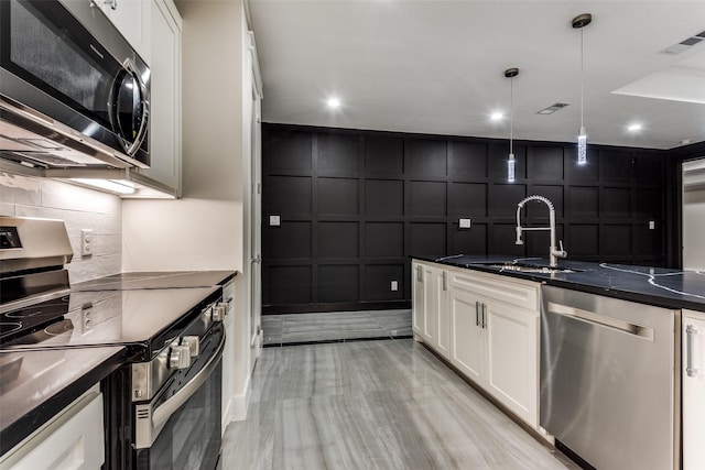 kitchen featuring visible vents, dark countertops, appliances with stainless steel finishes, a decorative wall, and a sink